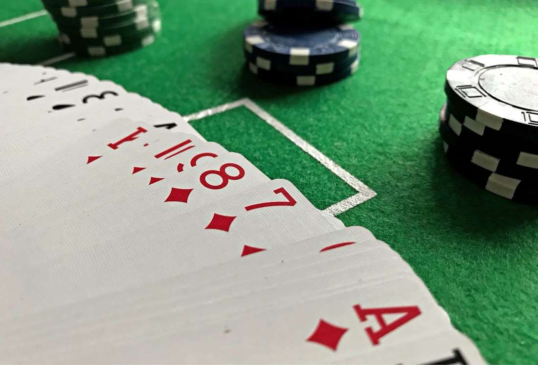 Susunan kartu remi dan chip di atas meja dengan cahaya redup