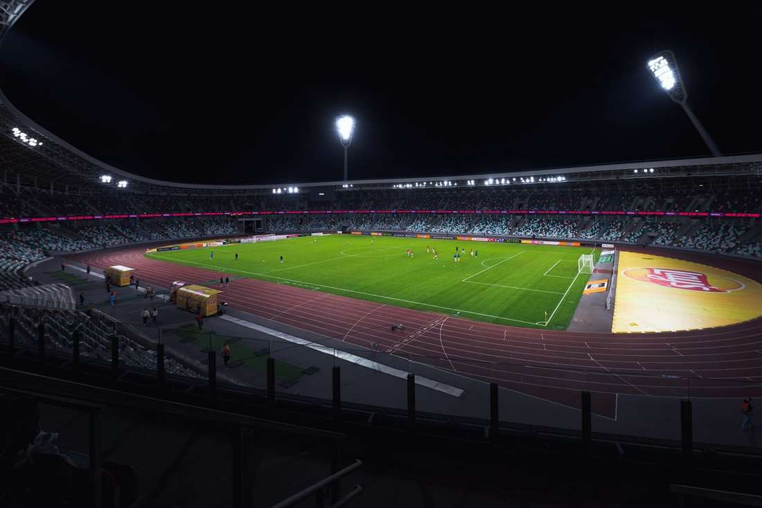 Stadion sepak bola menyala diterangi lampu sorot di malam hari